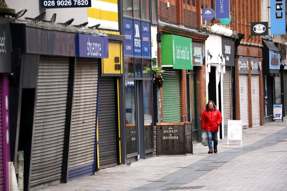 Мужчина проходит мимо закрытых магазинов на улице в центре Белфаста