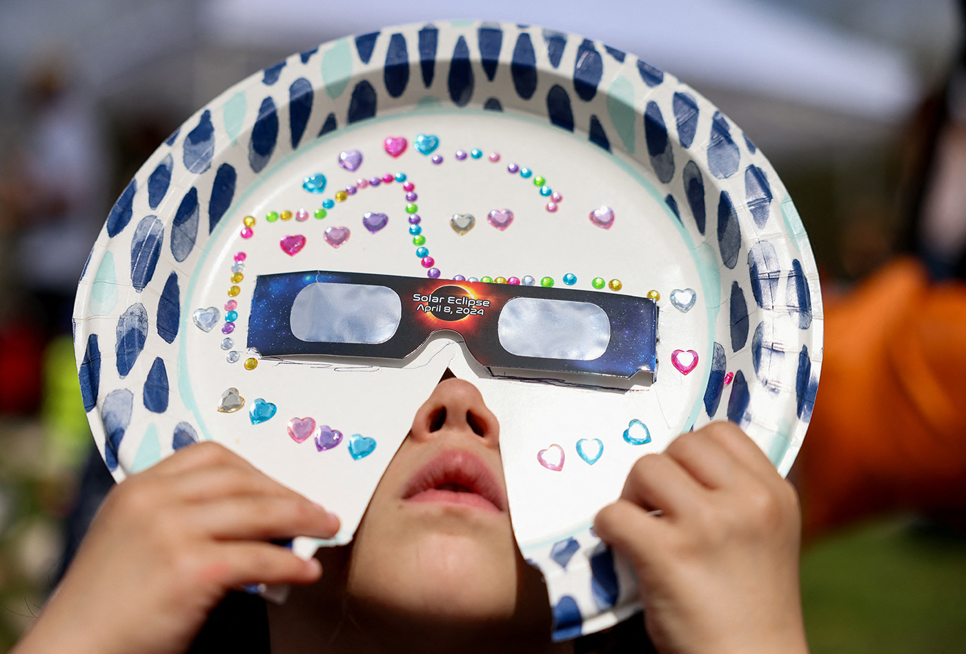 A girl from Queens views a partial solar eclipse with a homemade mask in New York City - 8 April 2024 (Andrew Kelly/Reuters)