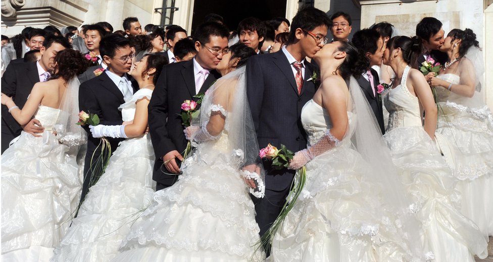 Молодожены молодые китайские пары целуются перед зданием мэрии Тура в долине Луары во Франции 10 октября 2008 года после свадебной церемонии, отмеченной мэром города.