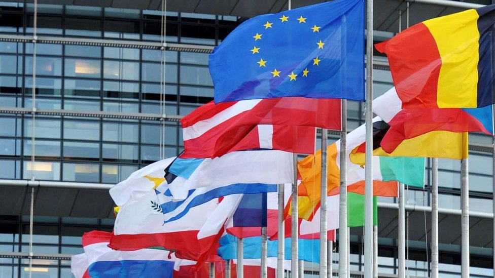 Bandeiras de vários países da União Europeia em frente a prédio