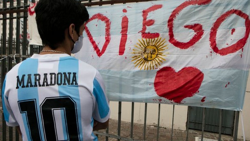 A fan wearing a Maradona Argentina shirt looks at a tribute in Buenos Aires