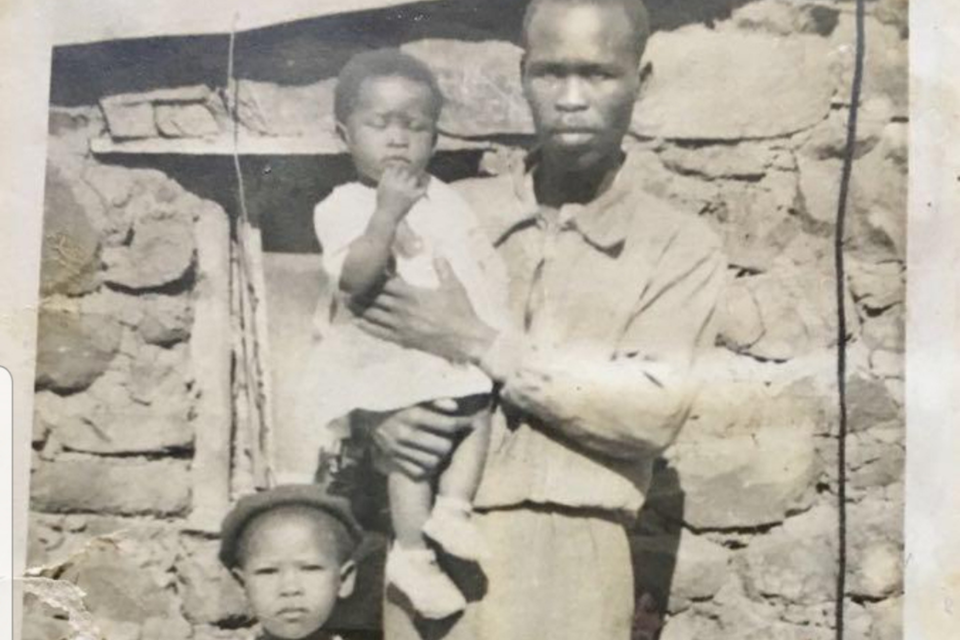 A photo of Agnes Sithole with her younger sister and father outside the house she was born in