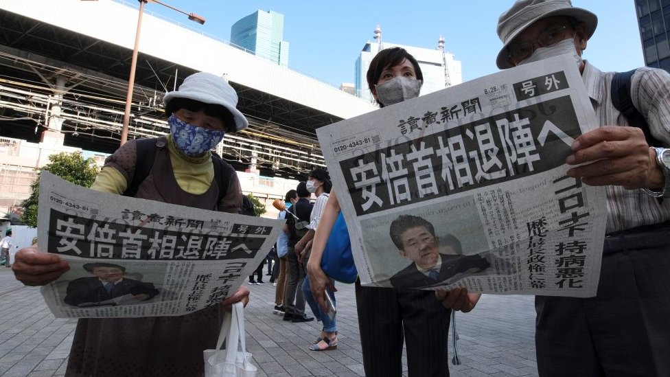Japoneses eleyendo en prensa sobre la renuncia de su primer ministro.