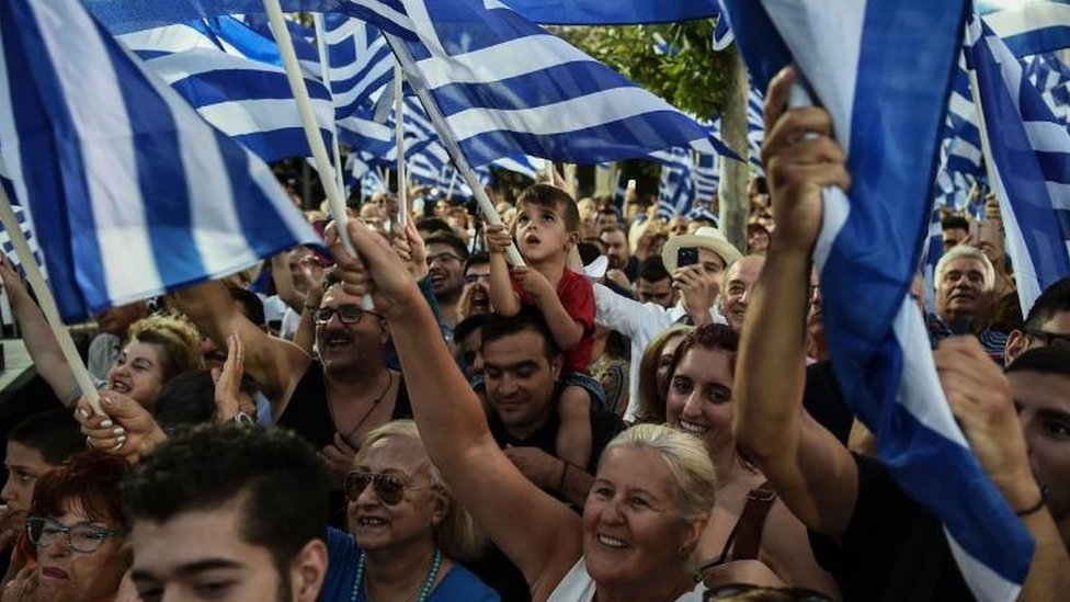 Сторонники греческой оппозиционной партии «Новая демократия» приветствуют и размахивают национальными флагами Греции