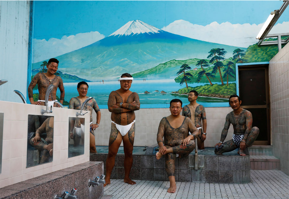 Группа мужчин с татуировками позируют в общественной бане