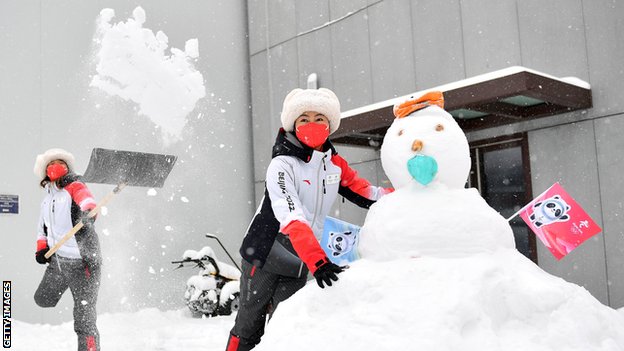 Olympic Games volunteers play with a snowman in Beijing