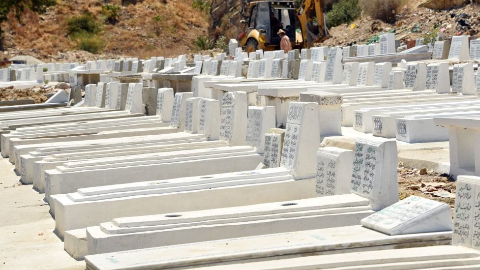 Gravediggers are seen working on a grave at the El Jalez cemetery in Tunisia