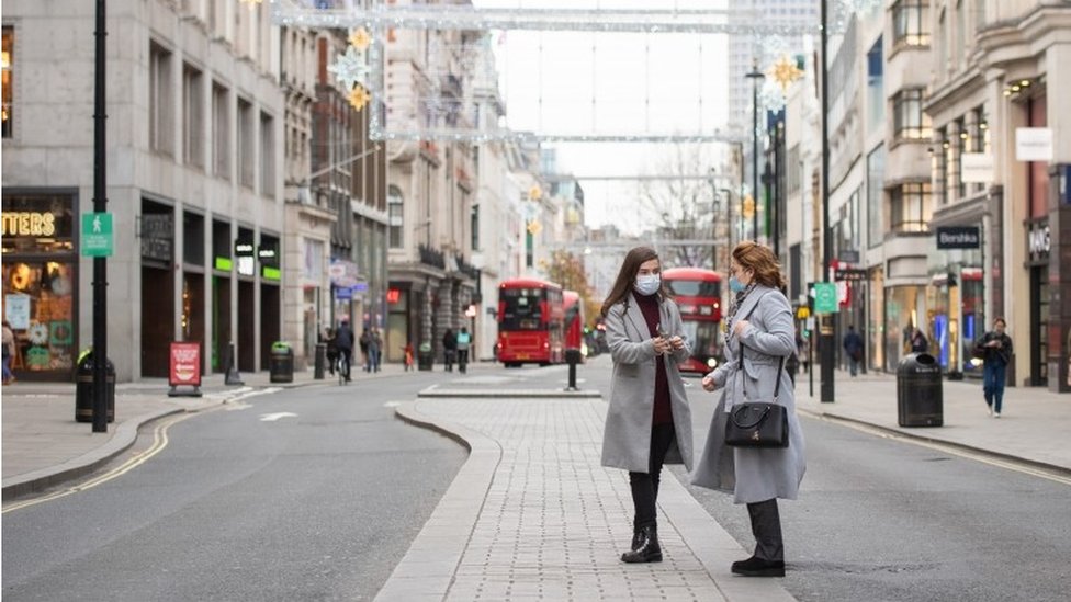 Два человека стоят посреди пустой Оксфорд-стрит