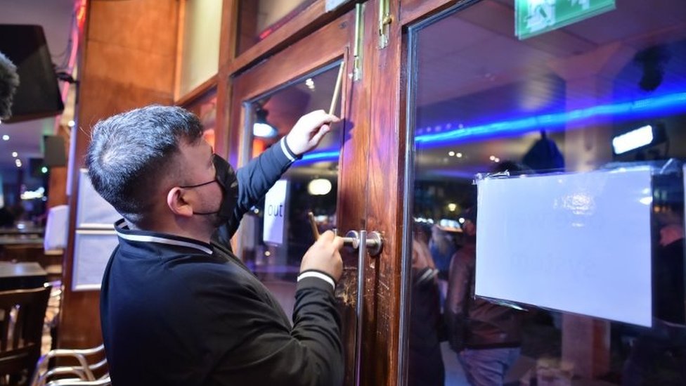 Рабочий закрывает двери в баре в центре Бристоля, в преддверии общенациональной блокировки Англии с четверга