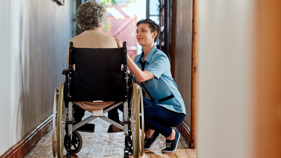 Сиделка помогает женщине в инвалидной коляске