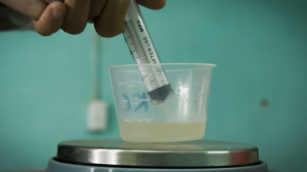 Añadiendo con una jeringa la bacteria a una solución de agua.