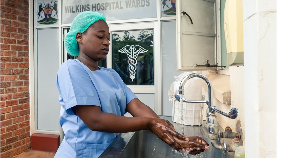 Медицинский работник моет руки в инфекционной больнице Уилкинса в Хараре 11 марта 2020 г.
