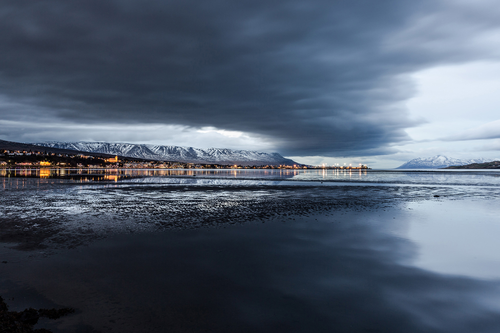Clouds reflected over water with snow-capped mountains in the distance