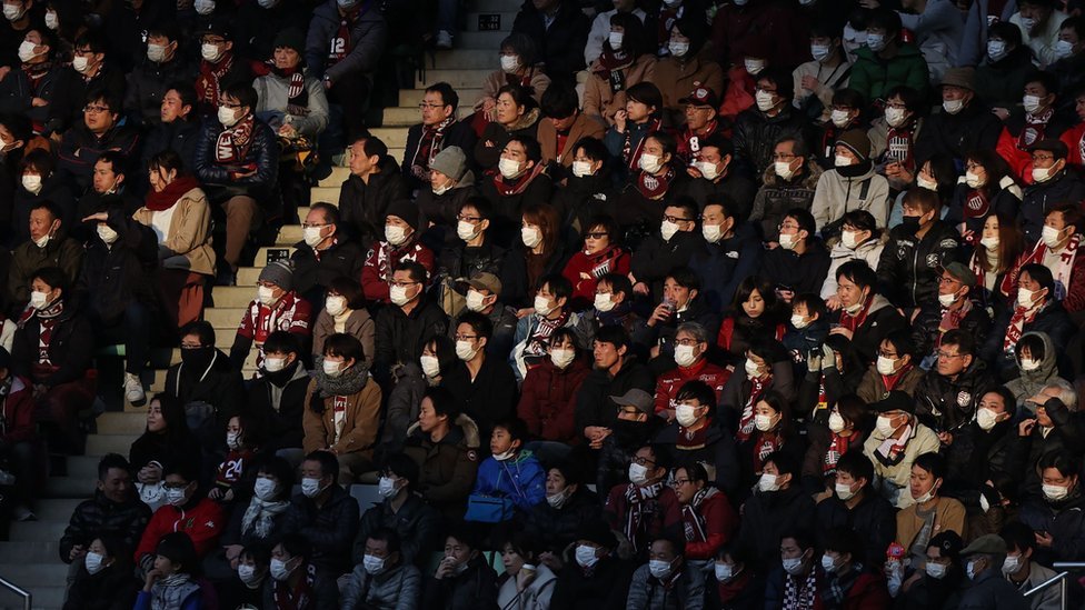 Aficionados durante un partido de fútbol en Japón llevando mascarillas.