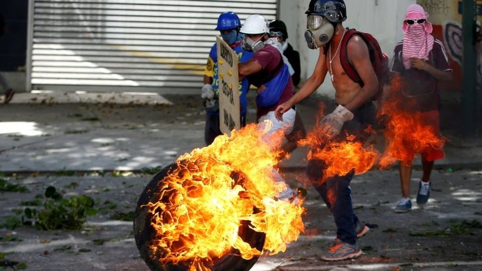 Демонстранты оппозиции используют горящую шину, чтобы заблокировать улицу в Каракасе. Фото: 26 июля 2017 г.