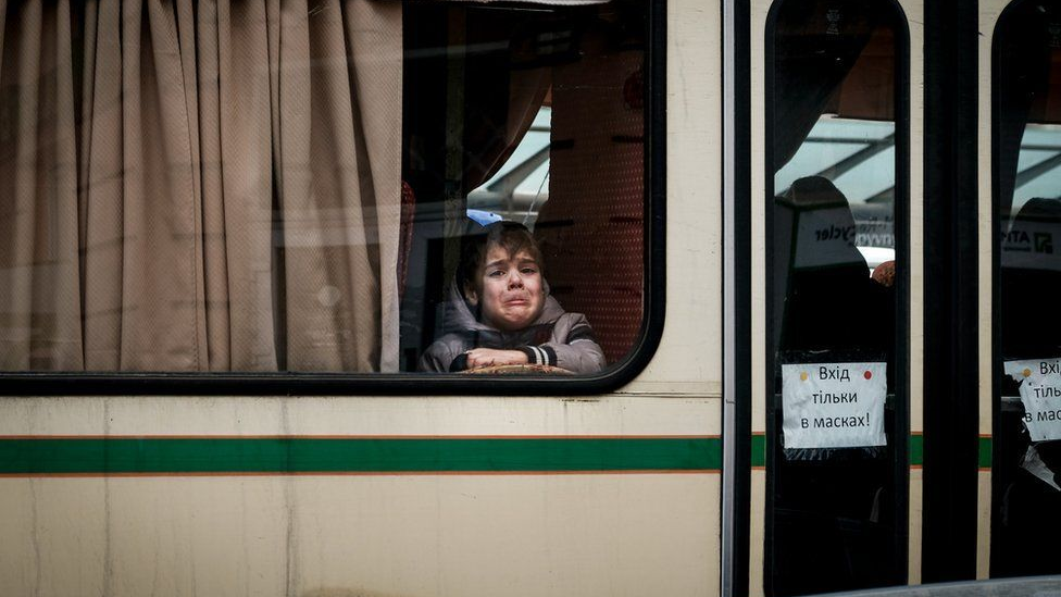 A crying child looking through a train window