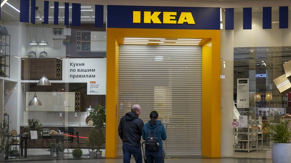A couple stand outside a closed Ikea shop in Moscow