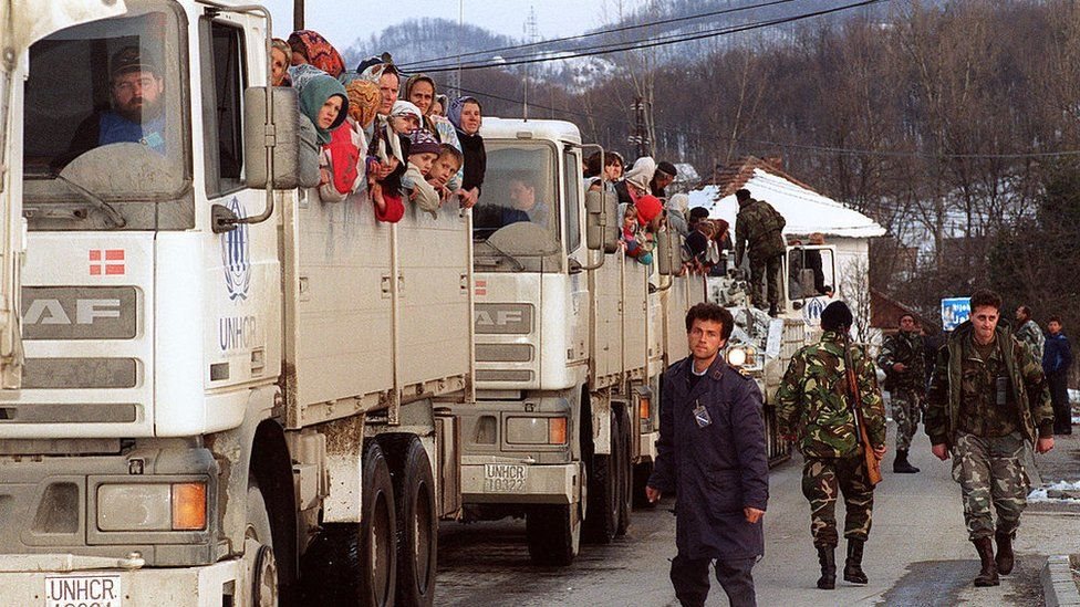 جنود يشرفون على عربات تابعة للأمم المتحدة وعلى متنها نسوة وفتيات وأطفال