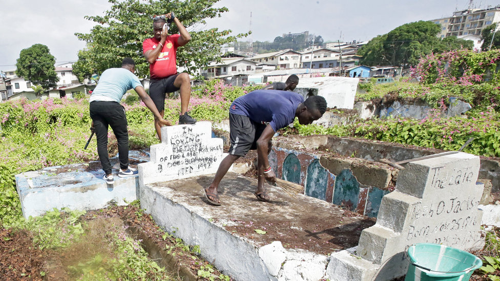 رجال يتولون تنظيف مقبرة في العاصمة الليبيرية، مونروفيا، يوم الأربعاء، في يوم عطلة عامة تعرف باسم يوم التزيين، عندما يذهب الناس لتنظيف قبور أقاربهم