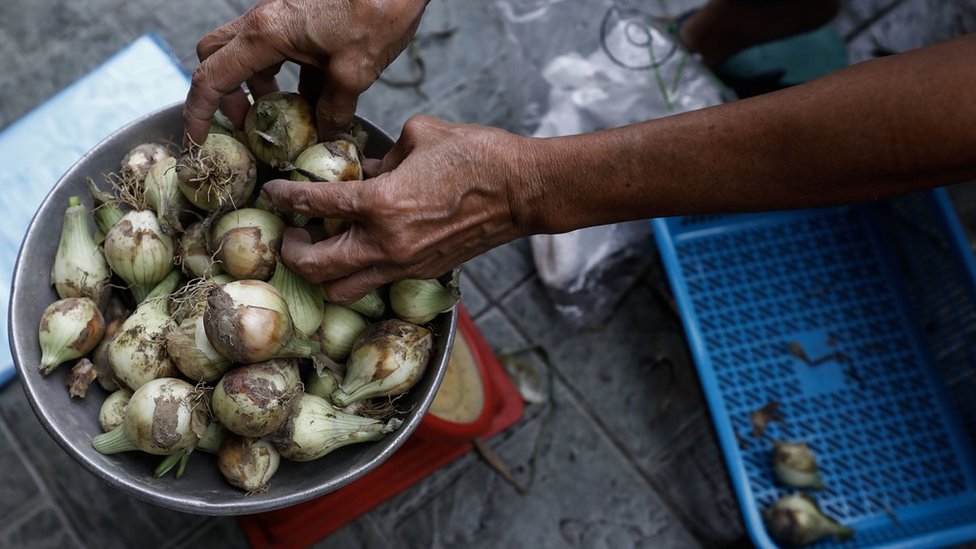 Person puts onions on a scale in Quezon City, Metro Manila, Philippines on January 10, 2023