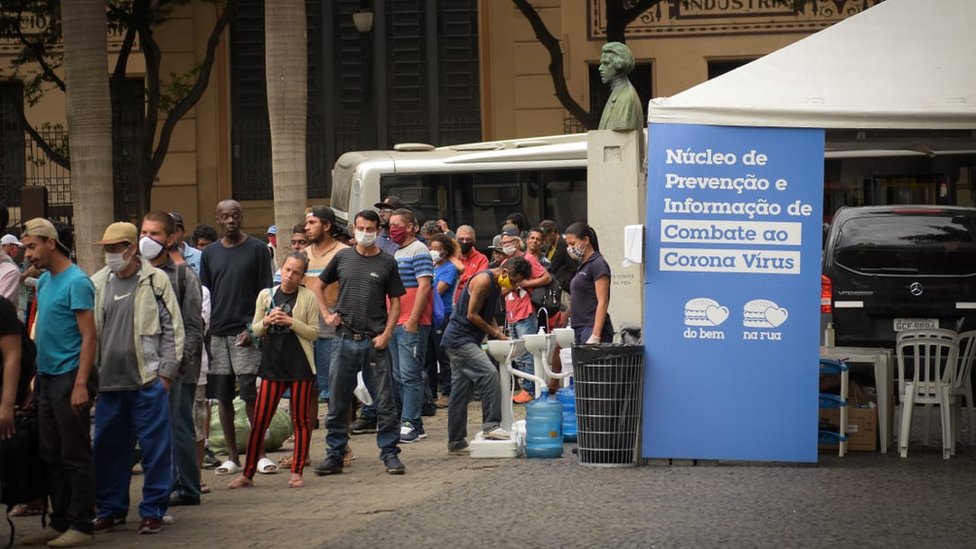 Pessoas se aglomeram em fila para receber refeição distribuída por padres franciscanos no largo São Francisco, no centro de São Paulo