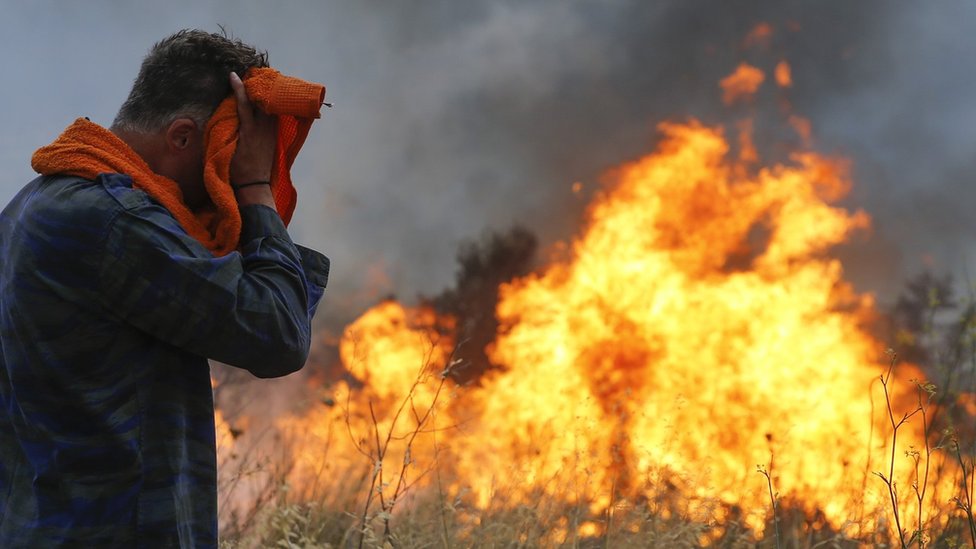 Bomberos y voluntarios intentan extinguir el fuego que se prendió en terrenos boscosos en Penteli, Grecia, el 23 de julio de 2018.