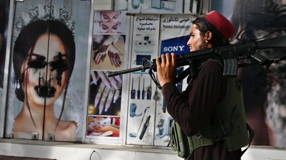 Un talibán pasa frente a un salón de belleza vandalizado