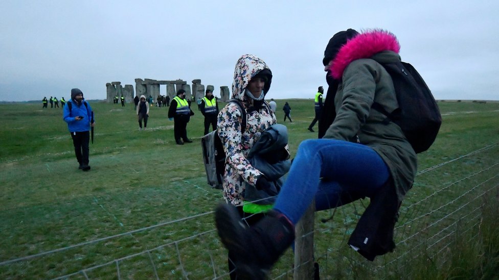 Revellers climb over a fence to get into Stonehenge ancient stone circle, despite official events being cancelled amid the spread of the coronavirus disease (COVID-19), near Amesbury, Britain, June 21, 2021.