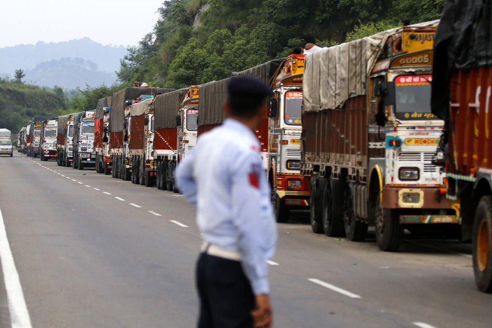 Полицейский смотрит на грузовики, застрявшие на шоссе Джамму-Сринагар в Нагроте, недалеко от Джамму, 9 августа 2019 г.,