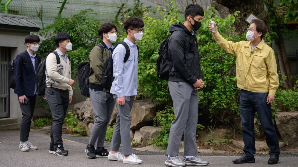 Students returning to school in Seoul in May, wearing face masks and having their temperature checked, after more than two months off due to the pandemic