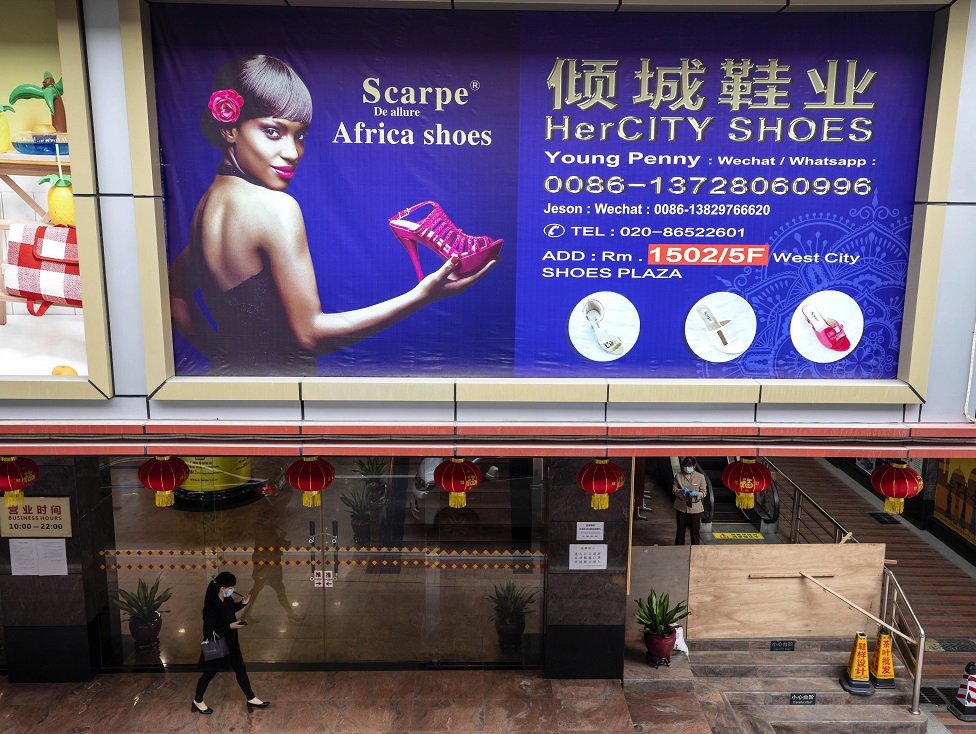 Женщина проходит мимо рекламного щита в части города, где живет и работает большинство африканцев, в Гуанчжоу, провинция Гуандун, Китай, 13 апреля 2020 года.