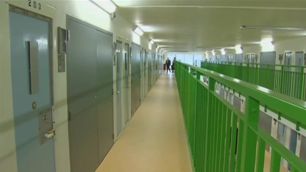 Крыло тюрьмы HMP Berwyn показывает длинный коридор с закрытыми дверями камер