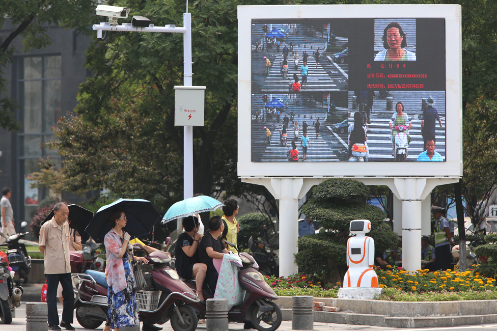 Equipo de reconocimiento facial y una pantalla diseñada para avergonzar a los peatones imprudentes en una concurrida intersección en Xiangyang el 26 de junio de 2017