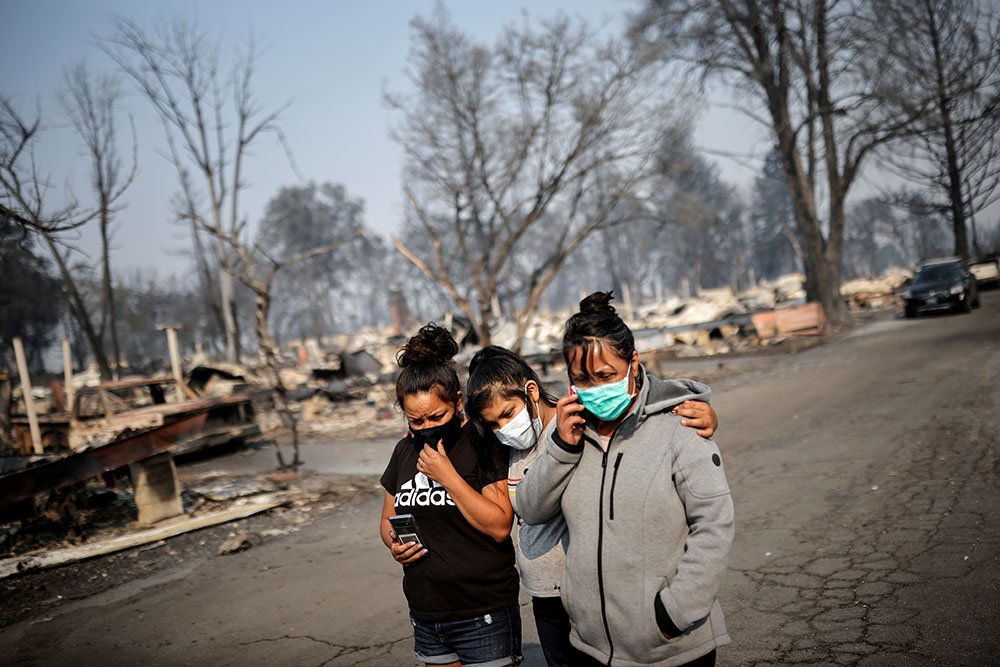 Sandra, Daniela, and Ester Reyes react while visiting their destroyed trailer home after the wildfires destroyed a neighbourhood in Bear Creek, Phoenix, Oregon