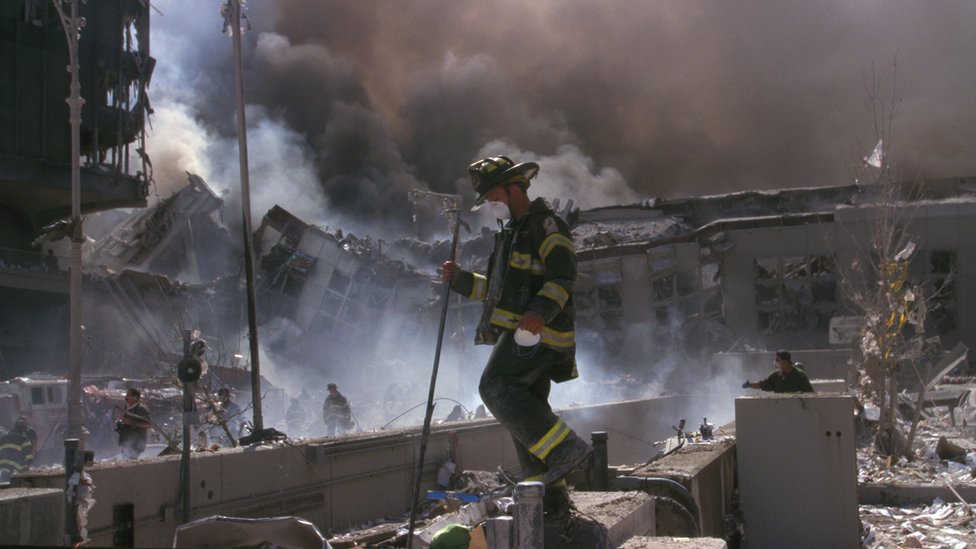 Пожарный идет через завалы после событий 11 сентября