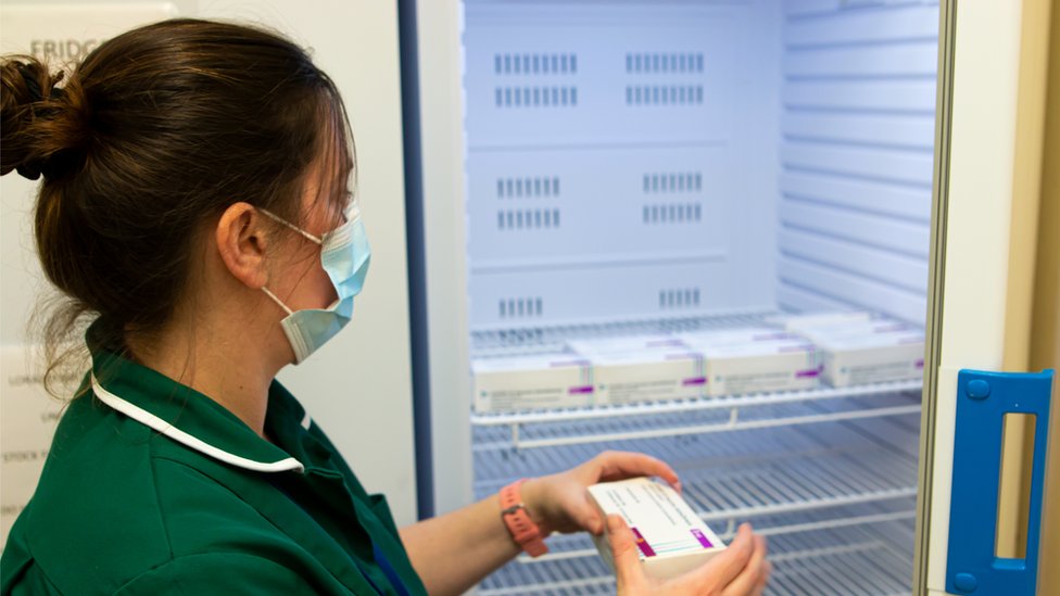 Медсестра кладет коробки с вакцинами в холодильник