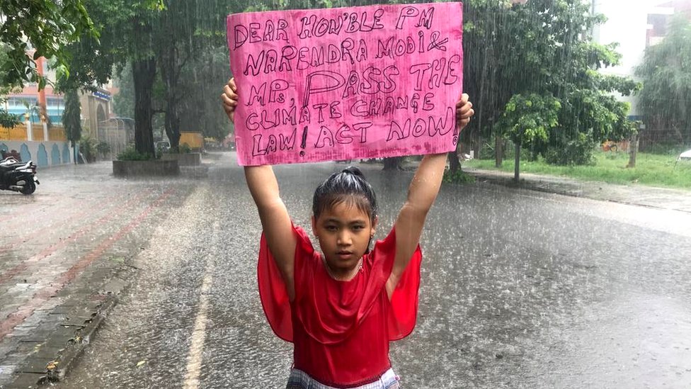 Восьмилетняя Лициприя Кангуджам стоит под дождем с плакатом, призывающим правительство Индии принять закон об изменении климата, 2019 г.