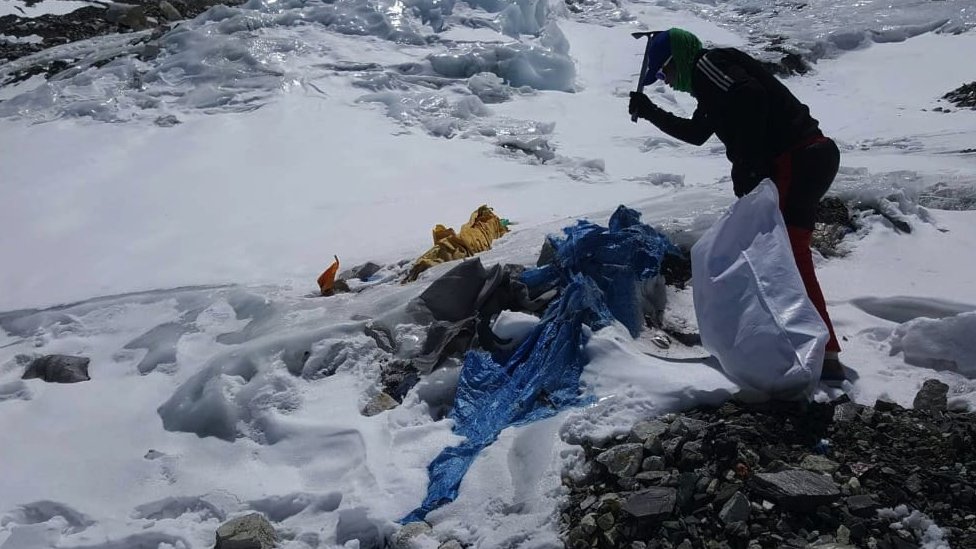 A member of a clean-up campaign clearing garbage left behind at Camp Three