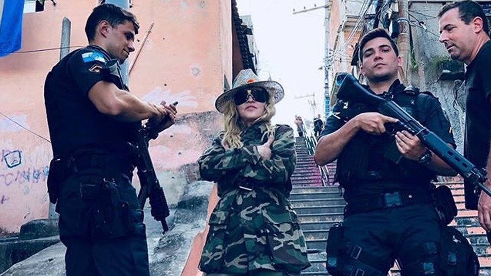 Мадонна позирует с военной полицией с оружием в трущобах Рио-де-Жанейро.