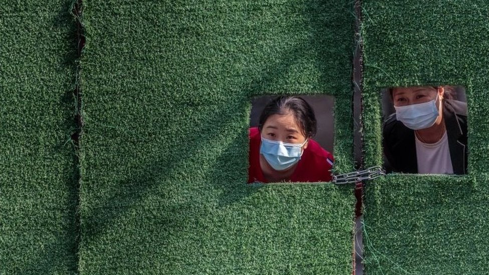 上海封城期間，因疫情被隔離的婦女透過柵欄窗朝外看