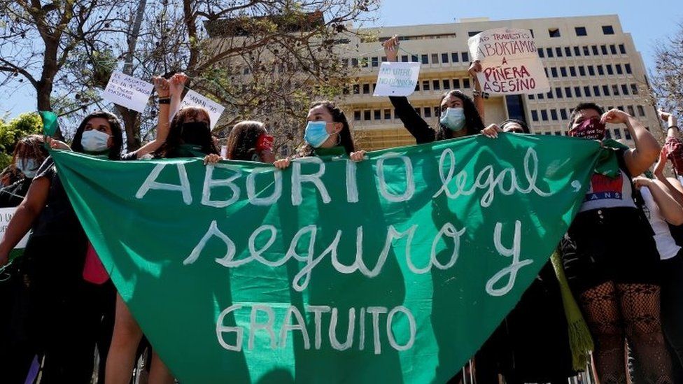Mujeres en Argentina con un gran pañuelo verde que dice "Aborto legal, seguro y gratuito"
