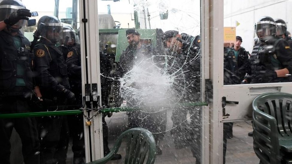 Miembros de la Guardia Civil española rompieron una de las puertas de un centro de votación en Sarria de Ter, donde se prevé que el presidente catalán, Carles Puigdemont, acuda a votar. Policía rompiendo una puerta
