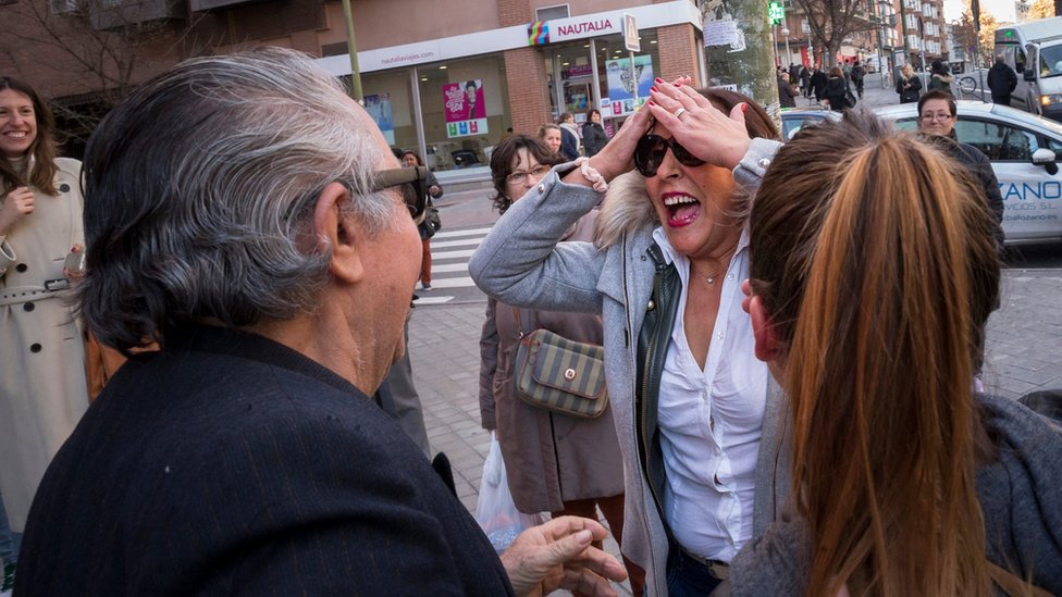 Люди празднуют возле лотерейного офиса вручения приза Эль Гордо (Толстяк) в Мадриде, Испания