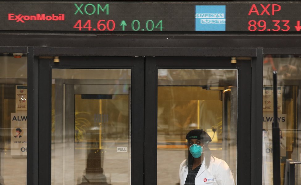 Женщина в маске перед биржей цен на акции