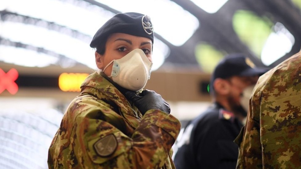 Военнослужащая Италии смотрит, как полиция проверяет людей на главном вокзале Милана. Фото: 9 марта 2020 г.