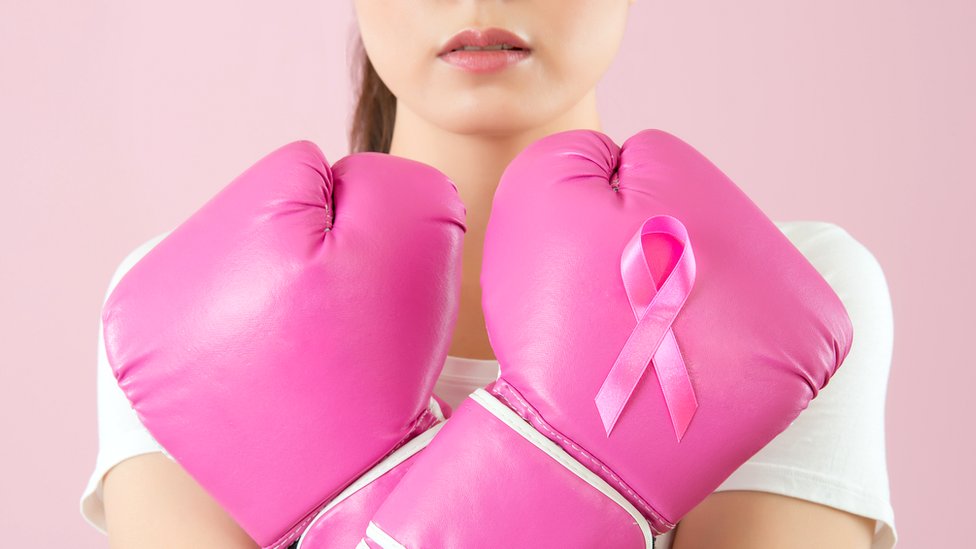 Mujer con guantes y el lazo rosa sobre la lucha del cáncer de mama.