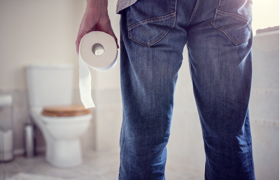 Algunos expertos aseguran que la postura más natural para ir al baño es sentarse en cuclillas. Un hombre sostiene un rollo de papel de baño.