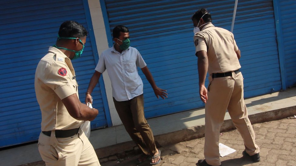 Офицер полиции размахивает дубинкой против человека в Мумбаи, Индия, 11 апреля 2020 г.