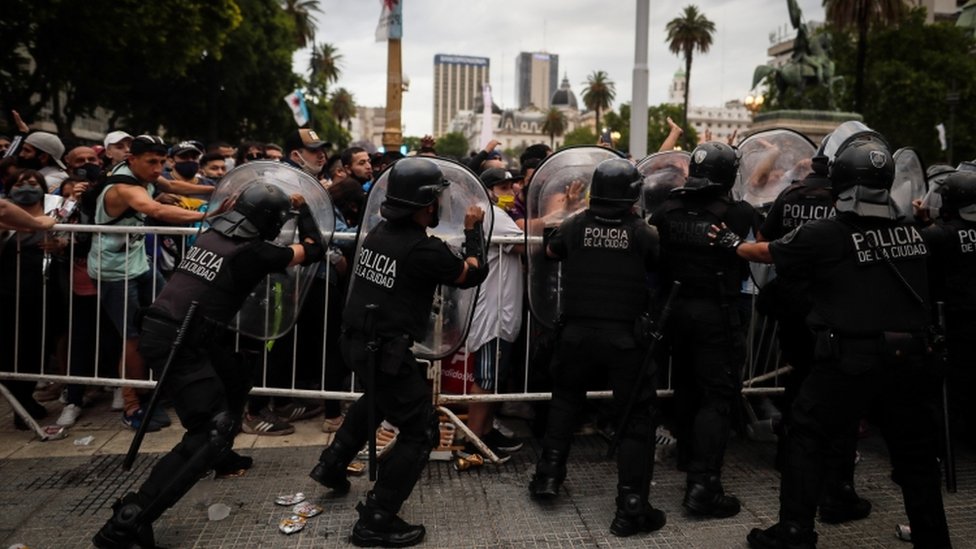 fans confront police as they wait to visit the coffin of Maradona