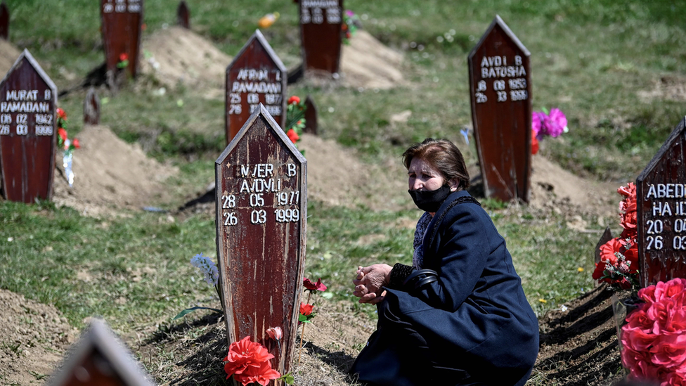 Una mujer arrodillada frente a la tumba de un albanokosovar que murió en 1999